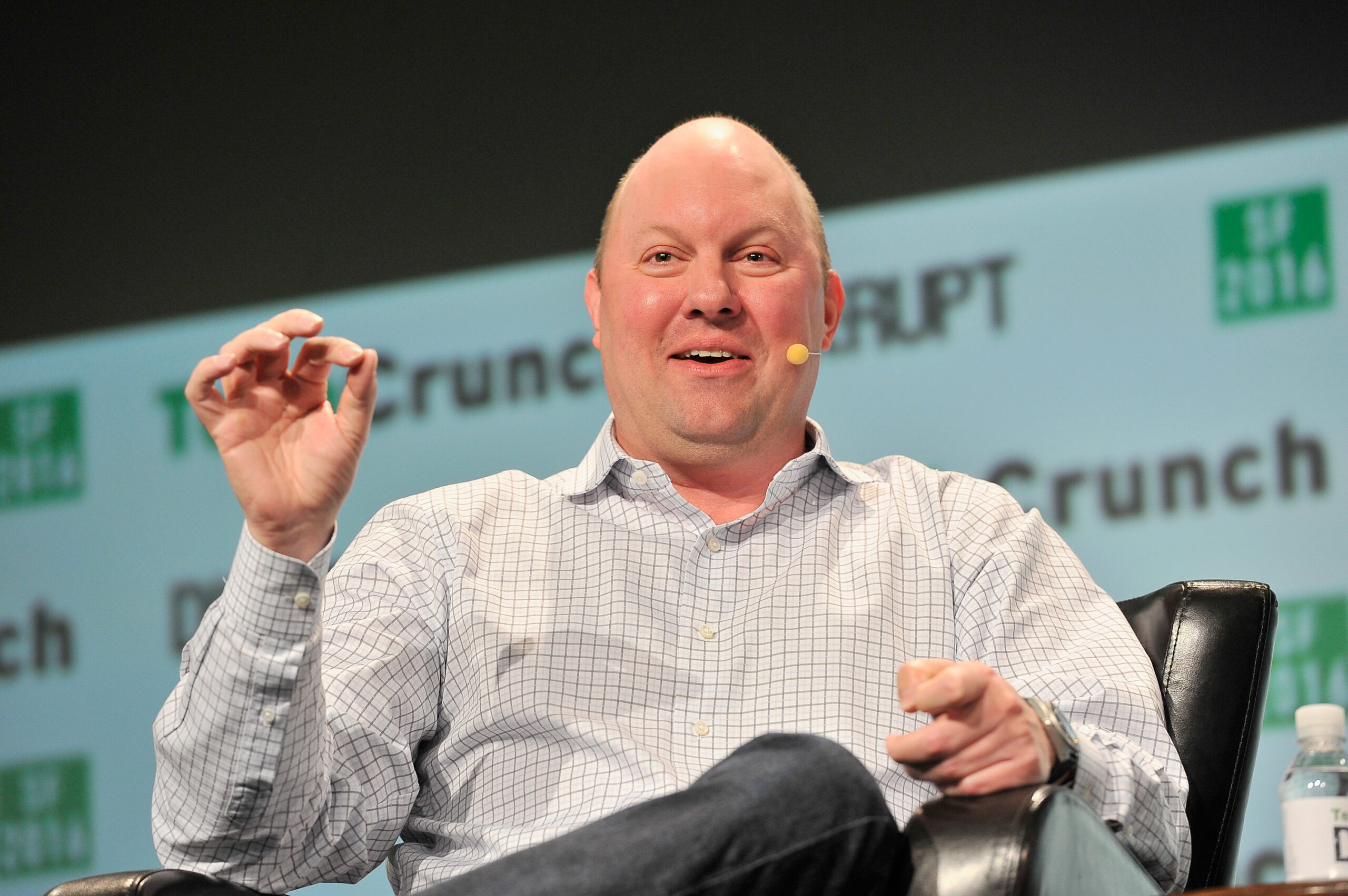 Marc Andreessen at a TechCrunch conference in 2013. He is sitting on a stage with a microphone attached to his jar and his right hand lifted to underline a point.